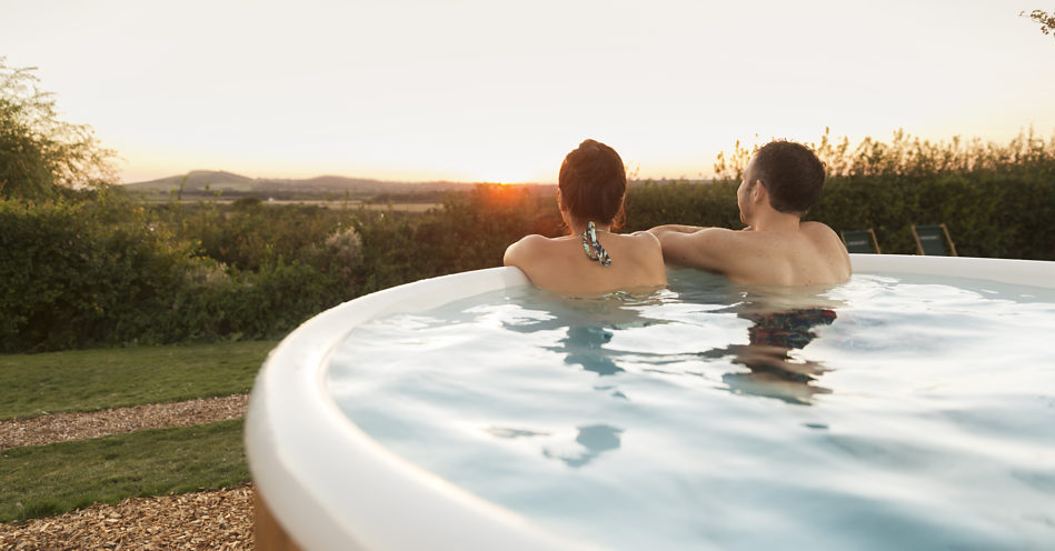 A close up of the back of a men and women, who are sitting in the hot tub and observing the surrounding area