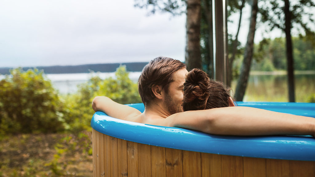 A couple enjoying a warm bath in a hot tub in Swedish nature