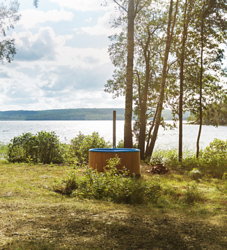 Distance shot of the Regal, a wood-burning hot tub from Skargards placed next to a lake in Sweden.